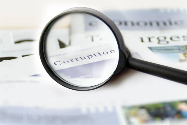 Corruption news concept showing a printed newspaper with a magnifying glass