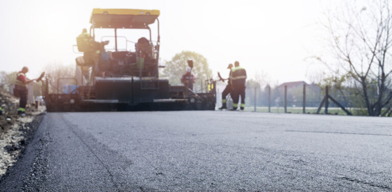 Workers placing new coating of asphalt on the road