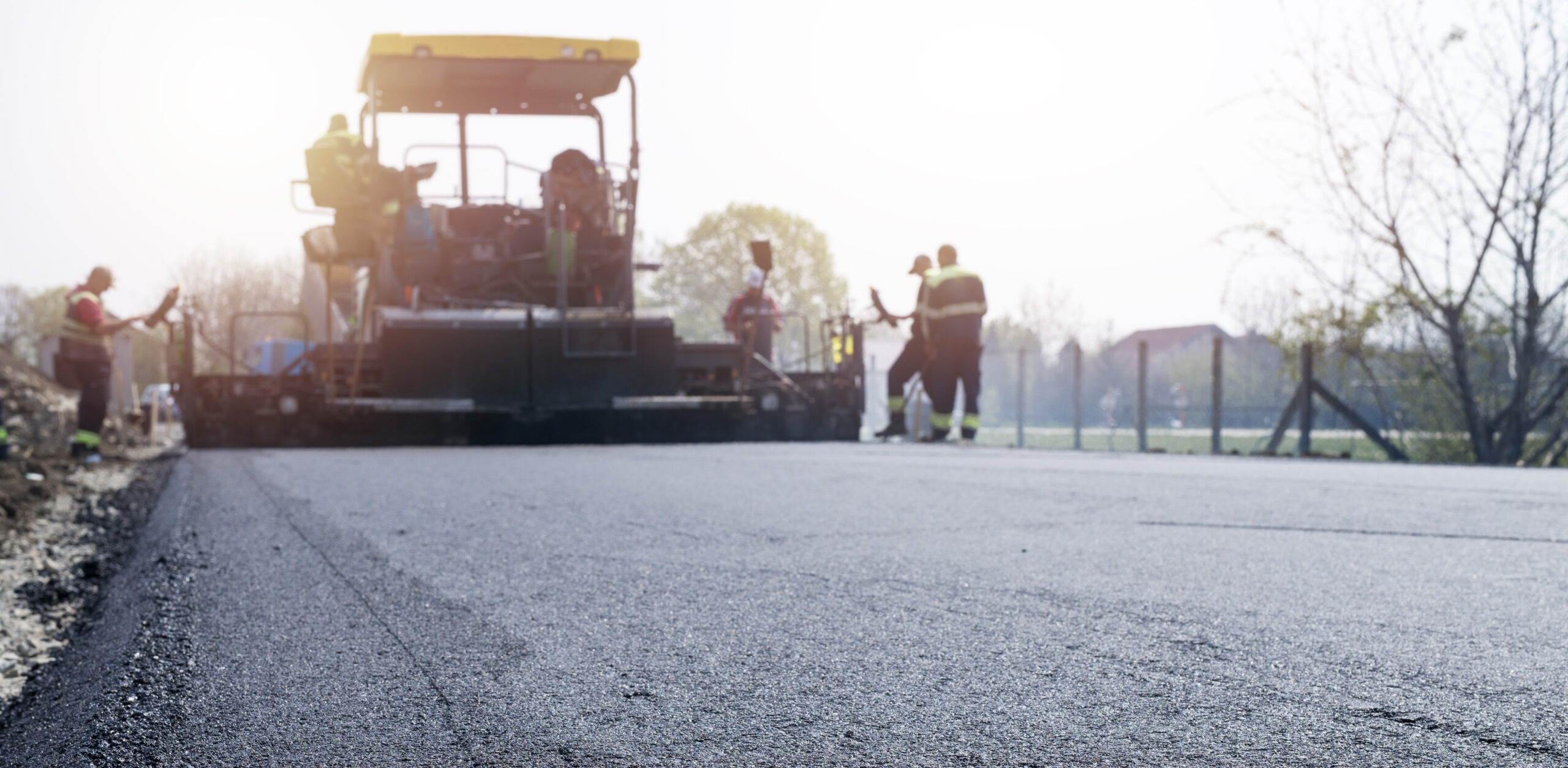 Workers placing new coating of asphalt on the road